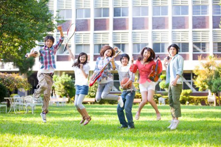 Photo for Happy group of students from music and sport sections jumping on green lawn - Royalty Free Image