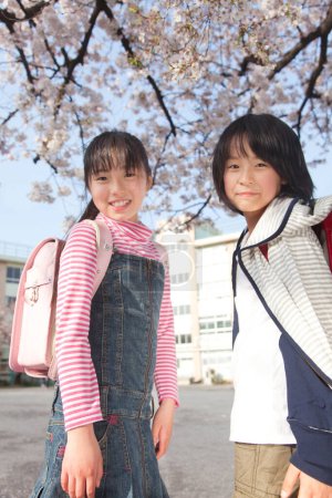 Foto de Sonrientes chicas japonesas con mochilas en el parque de primavera - Imagen libre de derechos