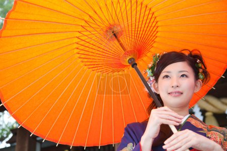 Foto de Hermosa joven japonesa en traje tradicional en el templo con paraguas de papel antiguo - Imagen libre de derechos
