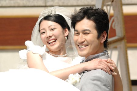 Foto de Feliz novia japonesa y novio posando para una foto - Imagen libre de derechos