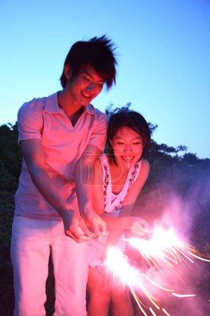 Photo for Happy Japanese man and woman holding sparklers in their hands - Royalty Free Image