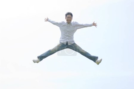 Téléchargez les photos : Jeune homme sautant haut sur fond de ciel bleu - en image libre de droit