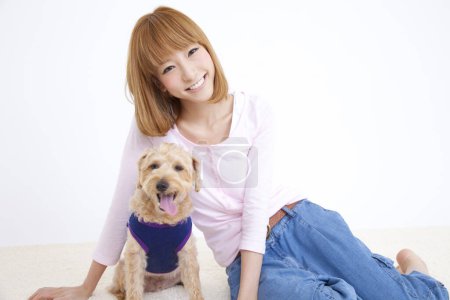 Photo for Beautiful asian woman with her dog, studio shot - Royalty Free Image