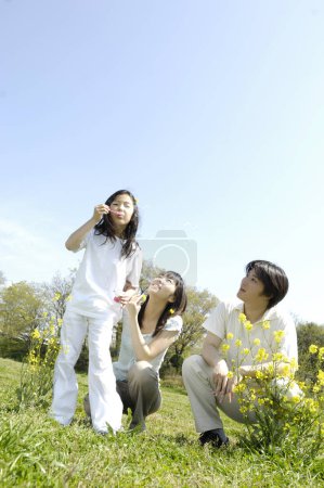 Foto de Familia joven soplando burbujas de jabón al aire libre - Imagen libre de derechos