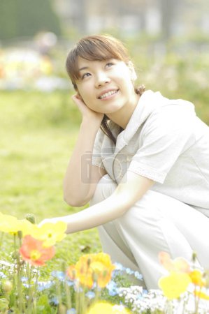 Téléchargez les photos : Jeune femme sur la pelouse avec des fleurs - en image libre de droit