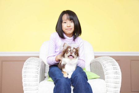 Téléchargez les photos : Souriant fille japonaise assis dans le fauteuil avec Chihuahua chien - en image libre de droit