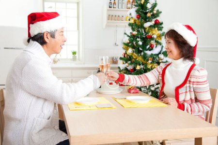 Photo for Asian senior man and woman toasting champagne on Christmas at home - Royalty Free Image