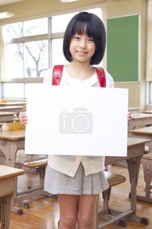 Foto de Joven estudiante sonriente con pancarta de papel en blanco en el aula - Imagen libre de derechos