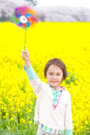 Foto de Retrato de lindo chico japonés con pinwheel posando cerca de campo de colza - Imagen libre de derechos