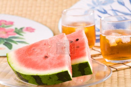 Foto de Primer plano vista de rodajas de sandía y té frío en la mesa. aperitivos y bebidas de verano - Imagen libre de derechos