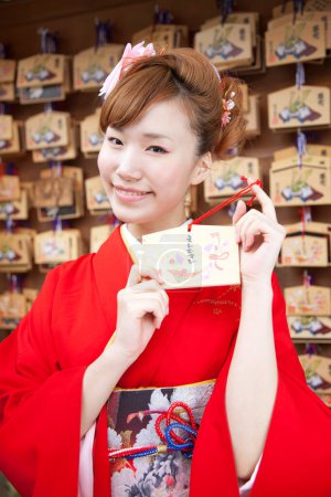 Photo for Beautiful japanese woman in kimono holding ema in shrine. - Royalty Free Image