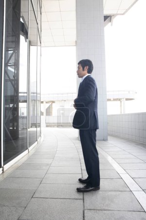 Téléchargez les photos : Un homme en costume debout devant un bâtiment - en image libre de droit