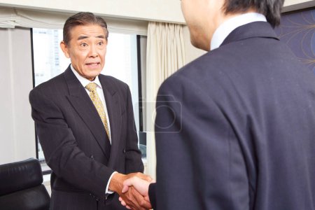 Photo for Two confident japanese managers shaking hands - Royalty Free Image