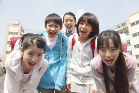 Téléchargez les photos : Groupe d'écoliers japonais avec professeur posant sur la cour de l'école - en image libre de droit