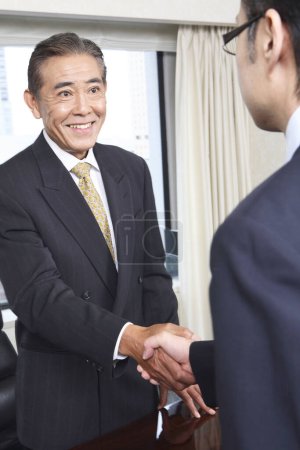 Photo for Two confident japanese managers shaking hands - Royalty Free Image