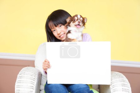 Téléchargez les photos : Sourire fille japonaise avec Chihuahua chien tenant papier vierge - en image libre de droit