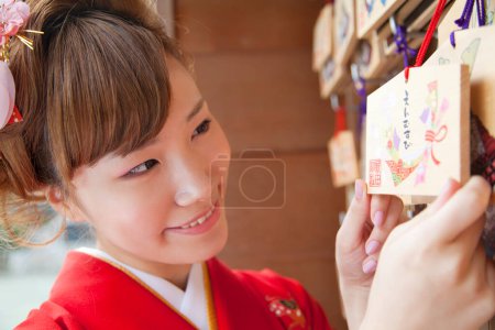 beautiful japanese woman in kimono holding ema in shrine. 