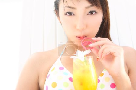 Photo for Asian woman in bikini drinking cocktail - Royalty Free Image
