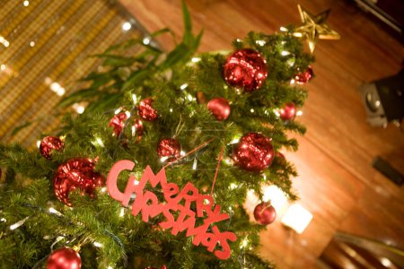 Photo for Closeup of small Christmas tree decorated with red balls and sign Merry Christmas - Royalty Free Image