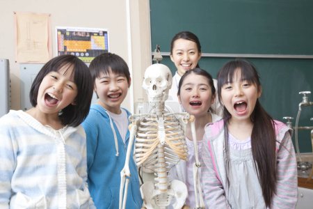 Photo for Group of happy schoolchildren in science class with skeleton and teacher - Royalty Free Image