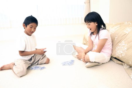 Foto de Joven asiático chico y chica con jugando a las cartas - Imagen libre de derechos