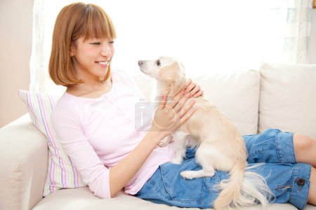 Photo for Young woman and dog on sofa at home - Royalty Free Image