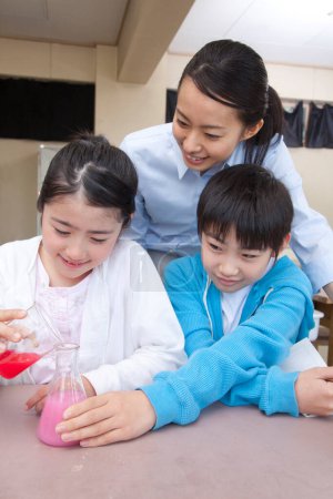 Photo for Japanese elementary school children doing chemical experiment with teacher in classroom - Royalty Free Image