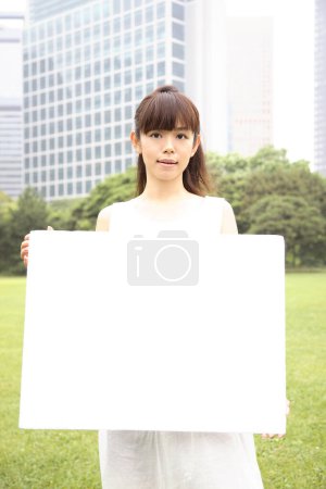 Photo for A woman holding a sign in a park - Royalty Free Image