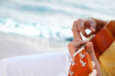 Photo for Asian man playing ukulele on sea shore - Royalty Free Image