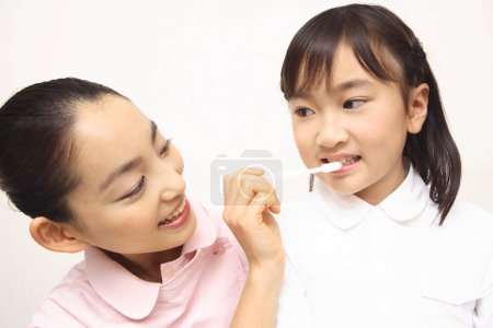 Téléchargez les photos : Japonais femelle dentiste enseignement mignon petite fille pour brosser dents - en image libre de droit