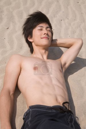 Photo for Handsome young man sunbathing on sandy beach - Royalty Free Image