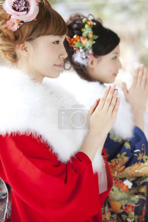 Asiático niñas vestidas en furisode orar en templo