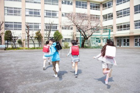 Foto de Grupo de alumnos de primaria con mochilas en marcha en la escuela, vista posterior - Imagen libre de derechos