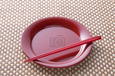 Téléchargez les photos : Plaque de céramique de style japonais et baguettes sur une table en bois. - en image libre de droit