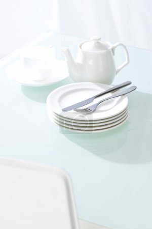 Téléchargez les photos : Théière, assiettes blanches, fourchette et couteau sur fond de table - en image libre de droit