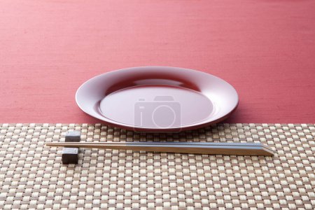 Téléchargez les photos : Assiette en céramique de style japonais et baguettes sur une serviette rose sur une table en bois. - en image libre de droit