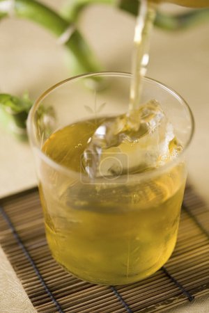 Téléchargez les photos : Verser du thé vert dans du verre avec de la glace - en image libre de droit