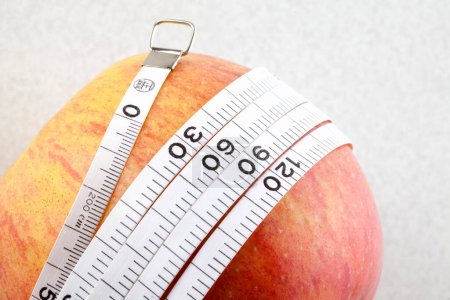 Téléchargez les photos : Pomme et ruban à mesurer sur fond blanc. Concept de régime - en image libre de droit