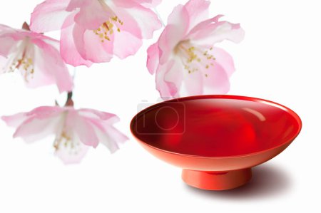 Téléchargez les photos : Bol rouge pour le saké japonais et fleurs de cerisier en fleurs, vue rapprochée - en image libre de droit