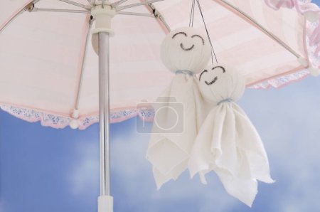 Photo for Umbrella and two cotton handmade dolls on a blue sky background, romantic toys made of white textile - Royalty Free Image