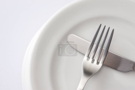 Photo for Fork and knife on a white plate - Royalty Free Image