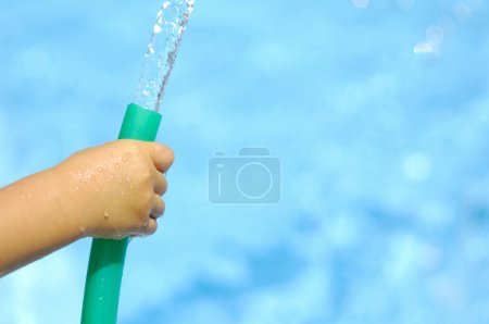 Foto de Hand holding green color hose and filling the pool with water - Imagen libre de derechos