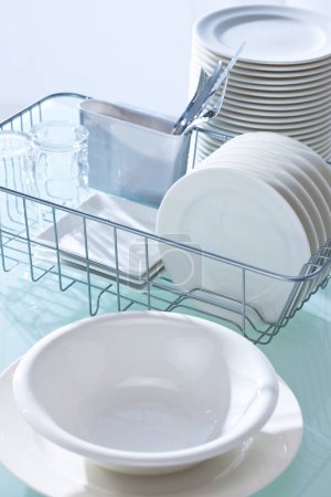 Foto de Platos limpios en lavavajillas estante en la mesa de la cocina limpia - Imagen libre de derechos