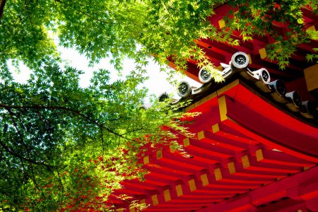 Téléchargez les photos : Façade rouge de l'architecture asiatique et branches d'arbres verts - en image libre de droit