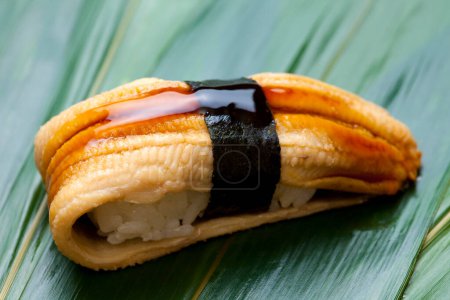 Téléchargez les photos : Rouleau de sushi japonais avec poisson anguille sur la feuille - en image libre de droit
