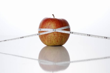 Photo for Apple and measuring tape on a white background. Dieting concept - Royalty Free Image