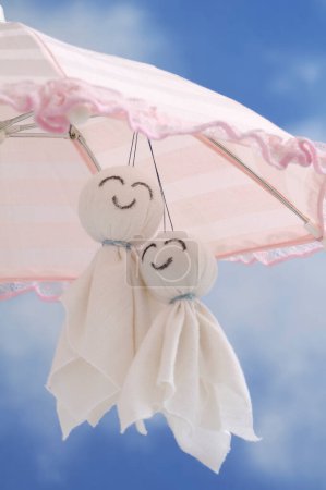 Foto de Paraguas y dos muñecas hechas a mano de algodón sobre un fondo de cielo azul, juguetes románticos hechos de textil blanco - Imagen libre de derechos