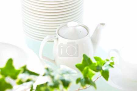 Photo for White ceramic teapot ,cup and plates on white table - Royalty Free Image
