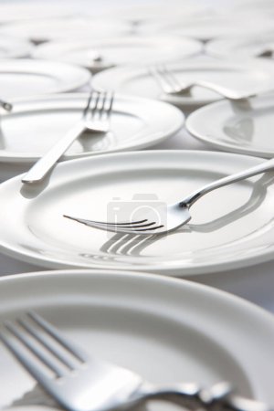 Foto de Juego de platos limpios sobre fondo blanco. Tenedores en platos blancos - Imagen libre de derechos
