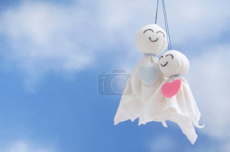 Téléchargez les photos : Deux poupées en coton faites à la main sur un fond bleu ciel, jouets romantiques en textile blanc - en image libre de droit